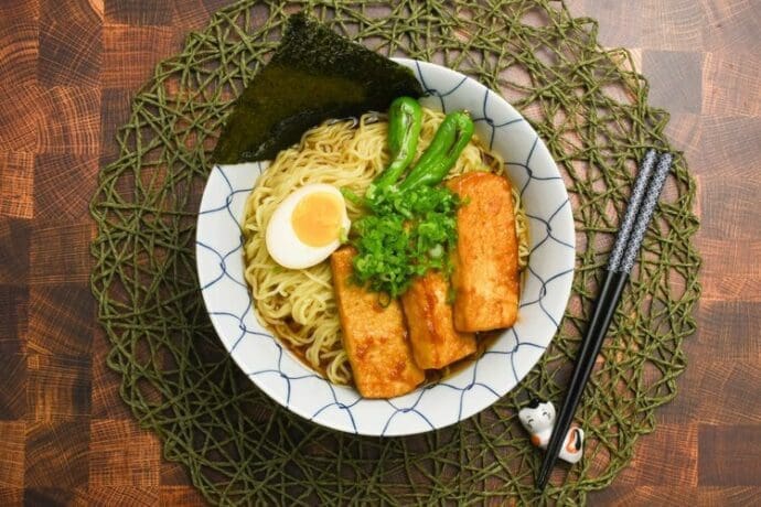 Premium Vegetarian Shoyu Ramen topping with tofu steak, shishito peppers, boiled egg, green onions, and seaweed (nori)