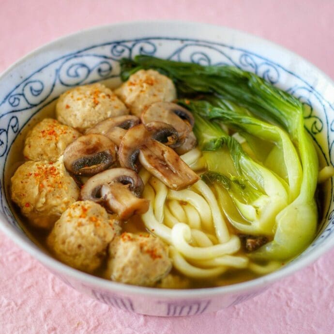 A bowl of hot Chicken Flavor Udon topping with tori dango (chicken dumplings or chicken balls), bok choy, and mushrooms