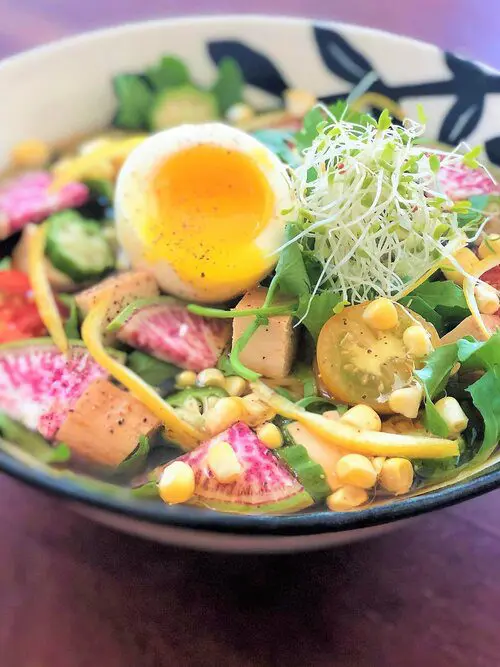 Ginger Rainbow Vegetarian Shoyu Ramen using Premium Vegetarian Shoyu Ramen topping with fresh arugula, crisp watermelon radish, okra, sweet corn, cherry tomatoes, and baked tofu