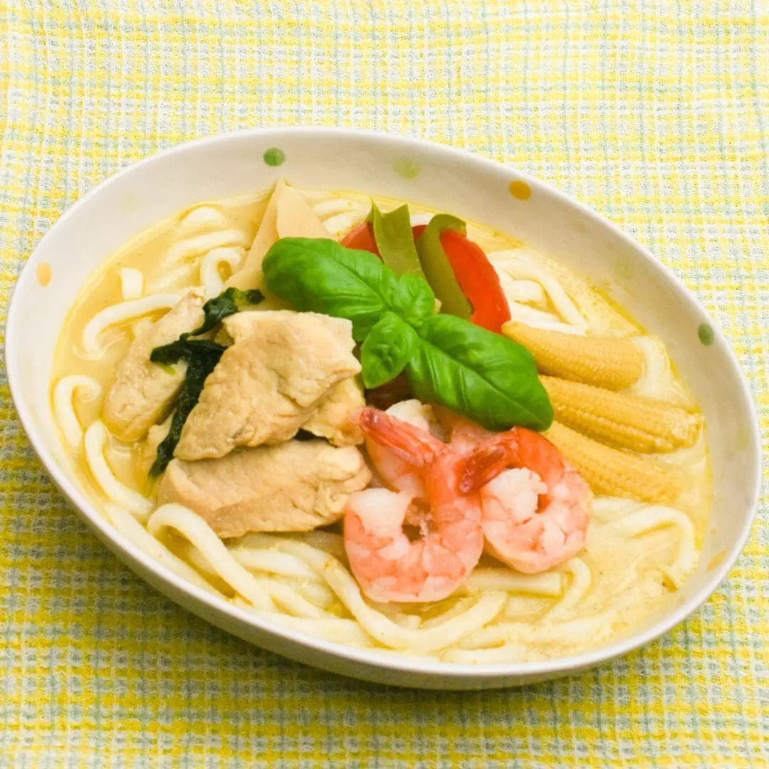 Green Curry (popular Thai cuisine) made with Udon, topping with chicken breast, baby corn, and shrimps