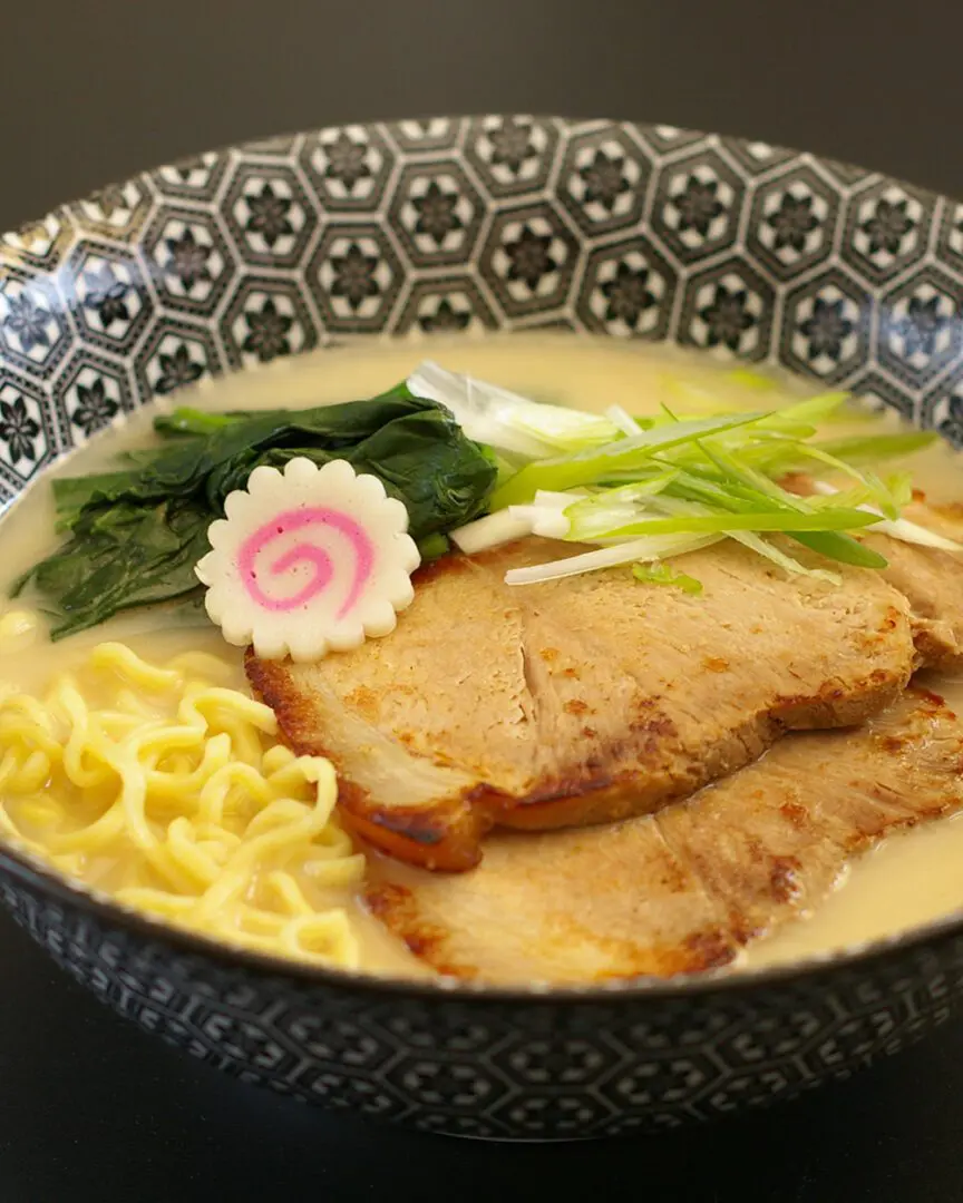 Premium Seafood Tonkotsu Ramen topping with slow-cooked chashu, naruto (fish cake), and spinach