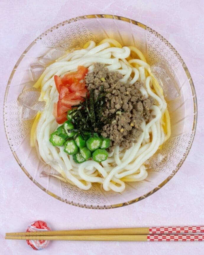 A bowl of cold udon topping with tomato, okras, and ground beef