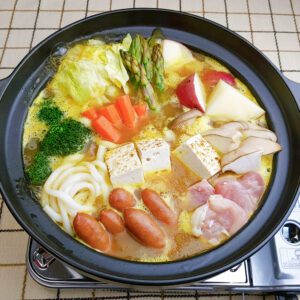 Curry hotpot cook with jumbo udon noodles only with chicken thigh, mini sausages, grilled tofu, cabbage, potatoes, eringi mushrooms, carrot, broccoli, and asparagus
