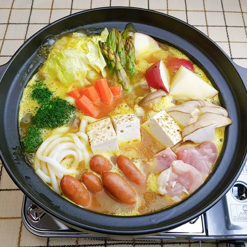 Curry hotpot cook with jumbo udon noodles only with chicken thigh, mini sausages, grilled tofu, cabbage, potatoes, eringi mushrooms, carrot, broccoli, and asparagus