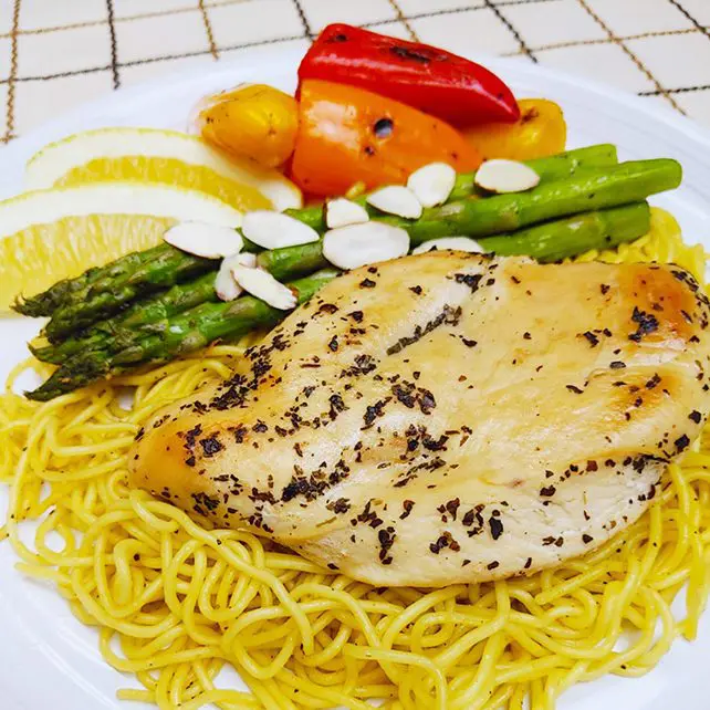 Lemon pepper chicken with yakisoba topping with asparagus, mini bell peppers, and almond slices