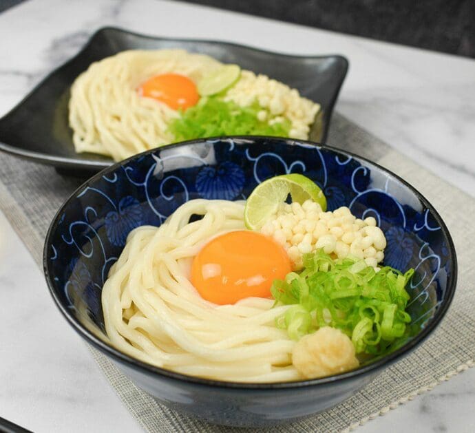 Fresh Udon noodles with a homemade tsuyu sauce topping with egg yolk, green onion, tenkasu (fried tempura bits), ginger and lime