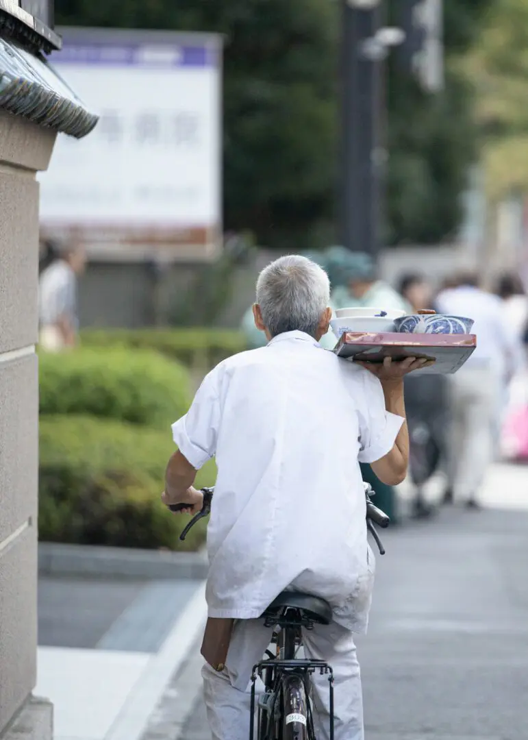 片手で出前を運ぶ自転車に乗った職人