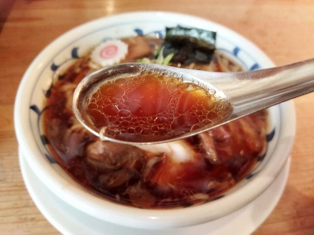 醤油ラーメンのスープをすくったレンゲのアップ
