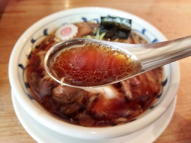 Close-up of spoon scooping shoyu ramen soup