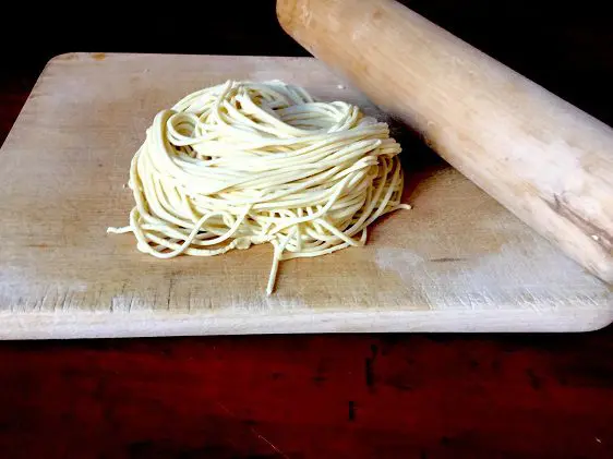 Cutting board and rolling pin with fresh ramen noodles on it